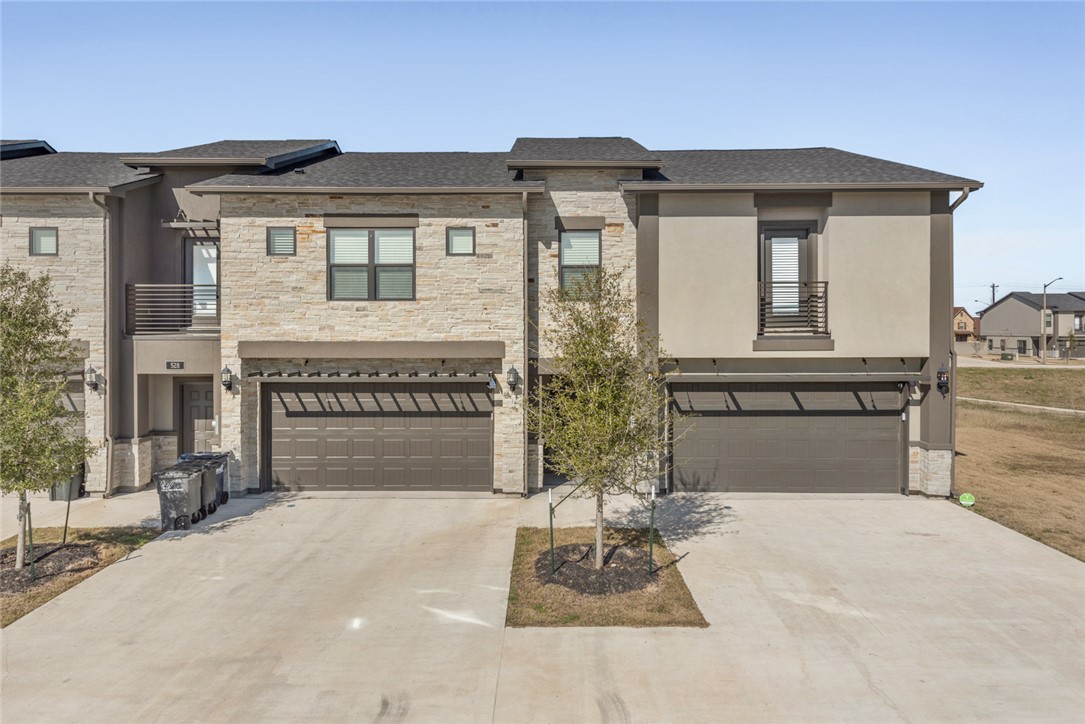 View of front of house featuring a balcony and a g