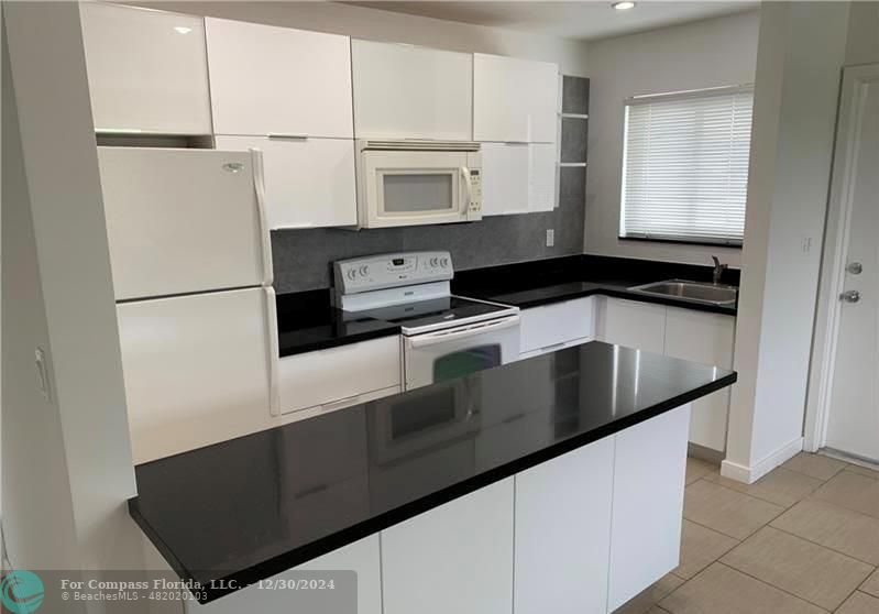 a kitchen with granite countertop white cabinets and white appliances