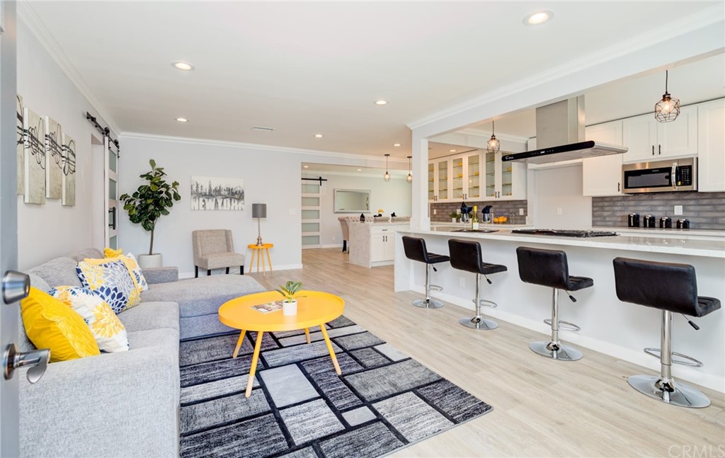 a living room with stainless steel appliances furniture and a kitchen view