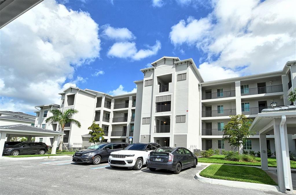 a front view of a building with lot of cars and trees