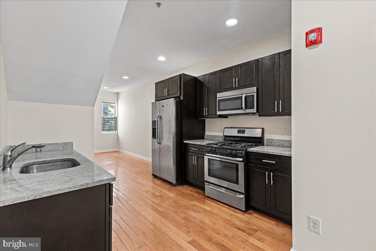 a kitchen with granite countertop a refrigerator stove and sink