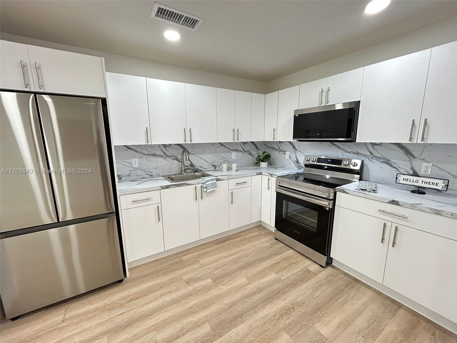 a kitchen with granite countertop a refrigerator stove and sink