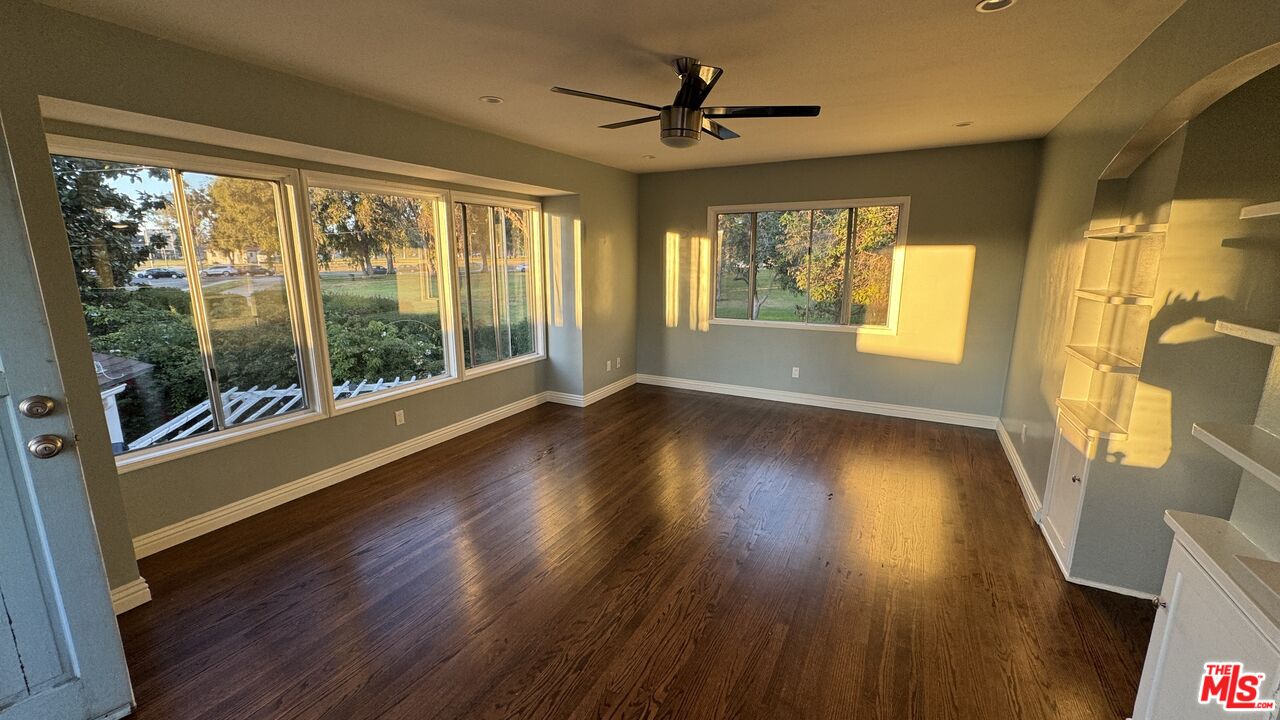 a view of empty room with wooden floor and fan