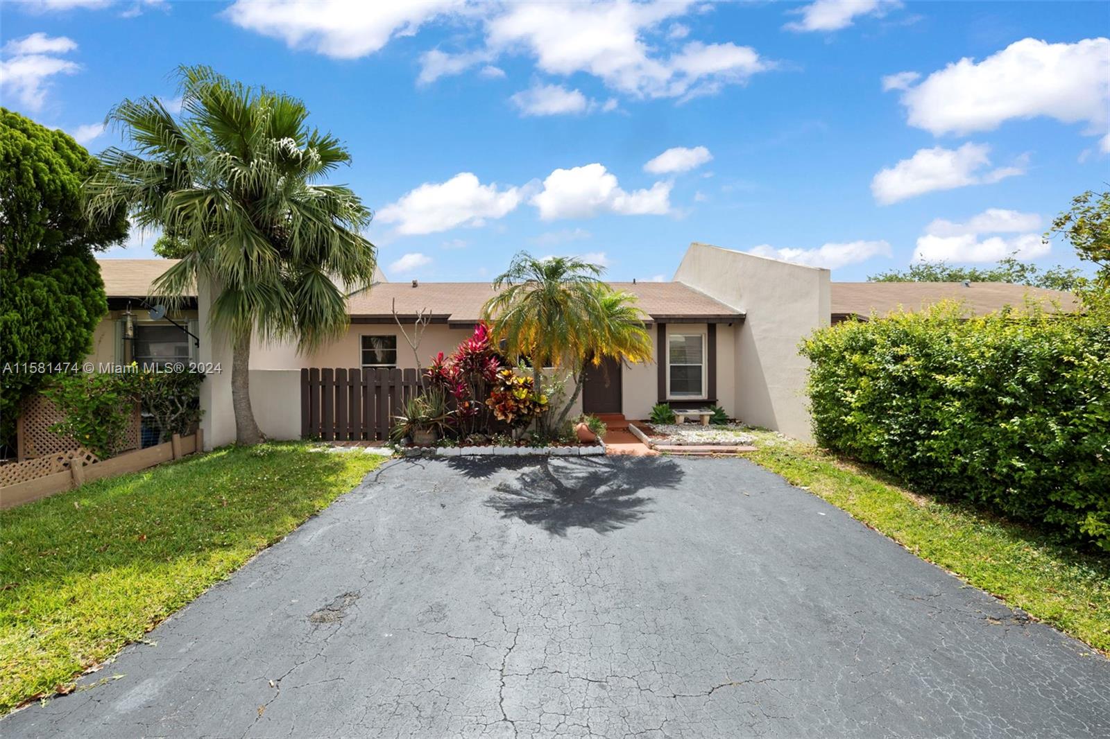 a view of a house with small yard plants and palm trees