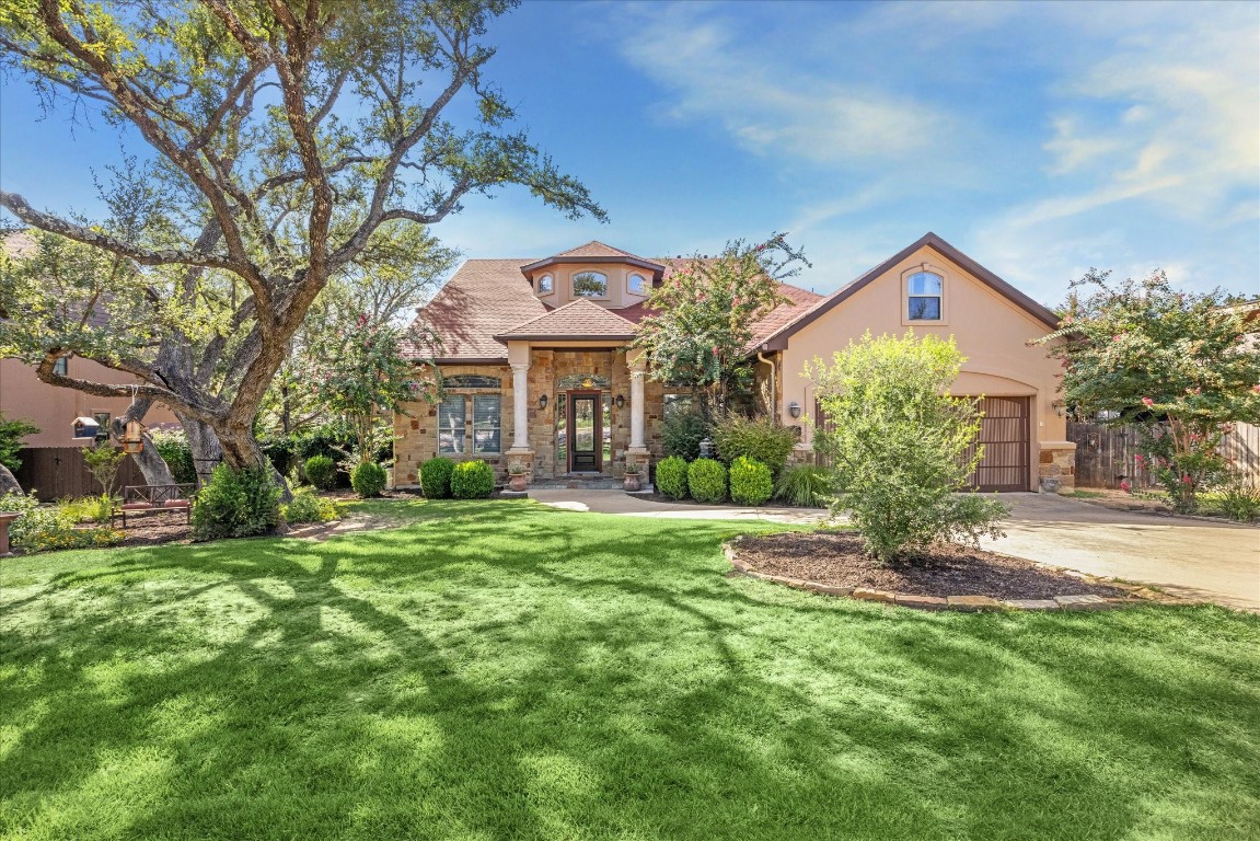 a front view of a house with a garden and tree