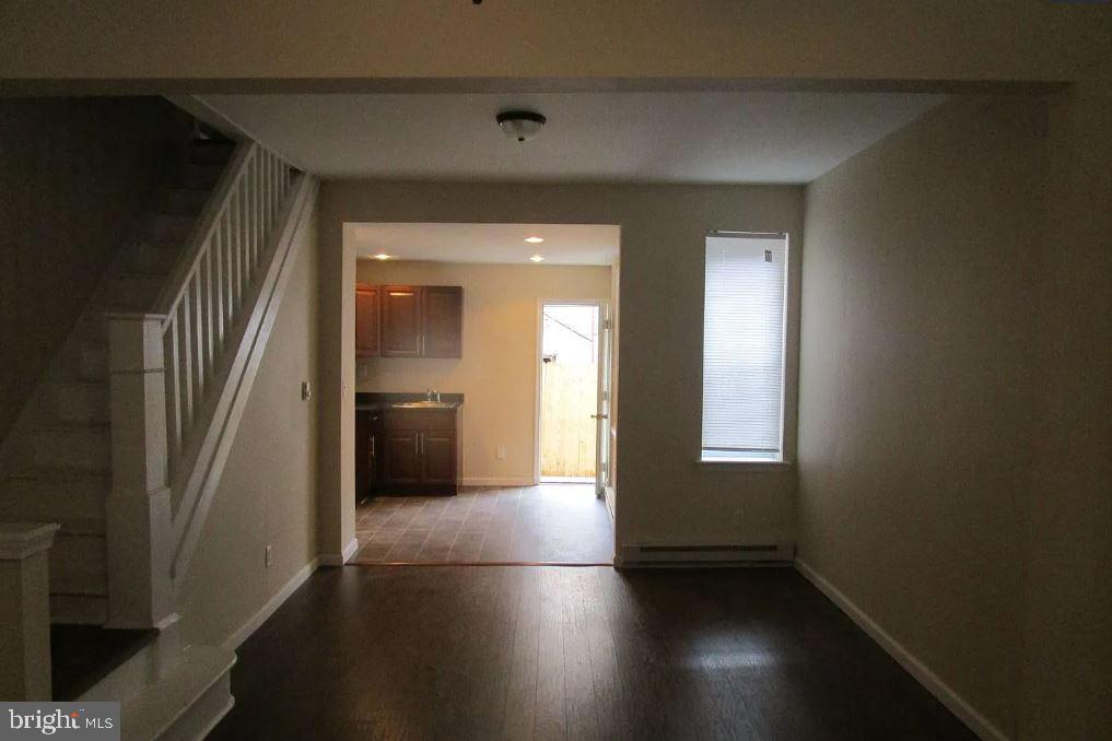 a view of a hallway with wooden floor and a bathroom