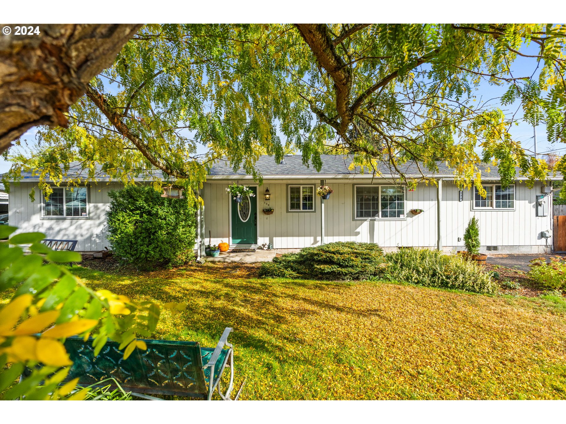 a view of yellow house with a big yard and large trees