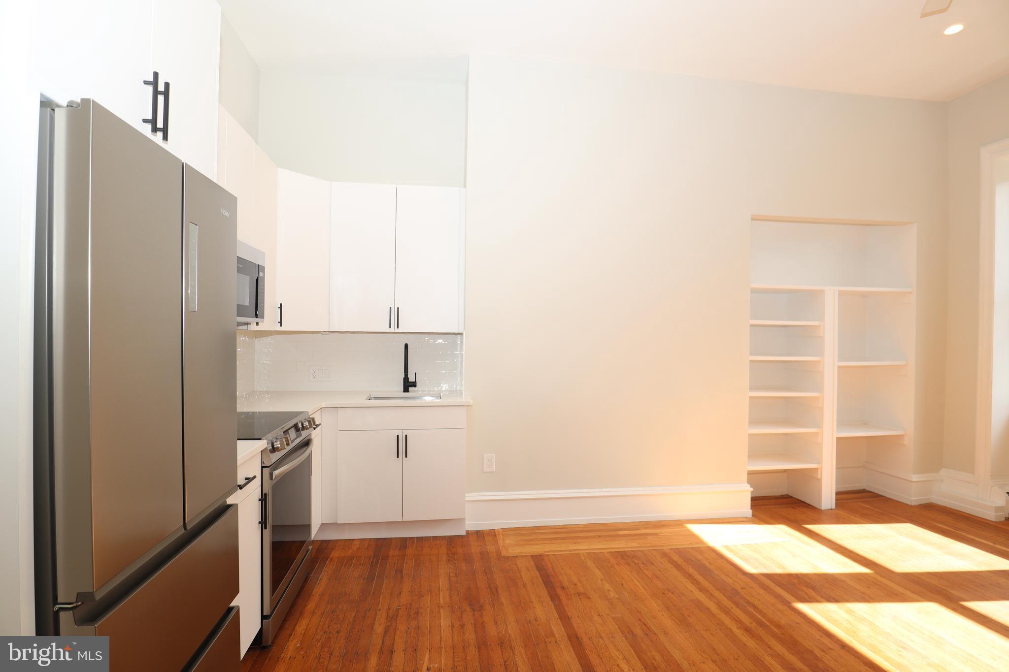 a kitchen with a sink wooden floor and a refrigerator