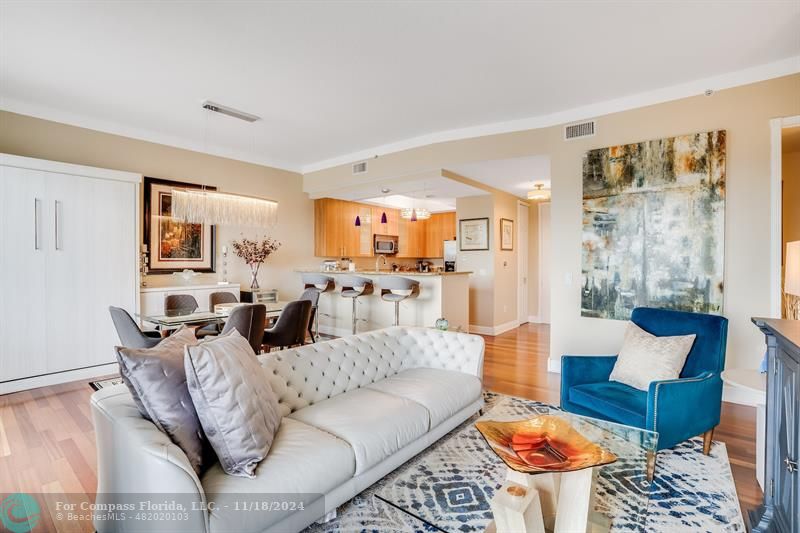 a living room with furniture wooden floor and a kitchen view