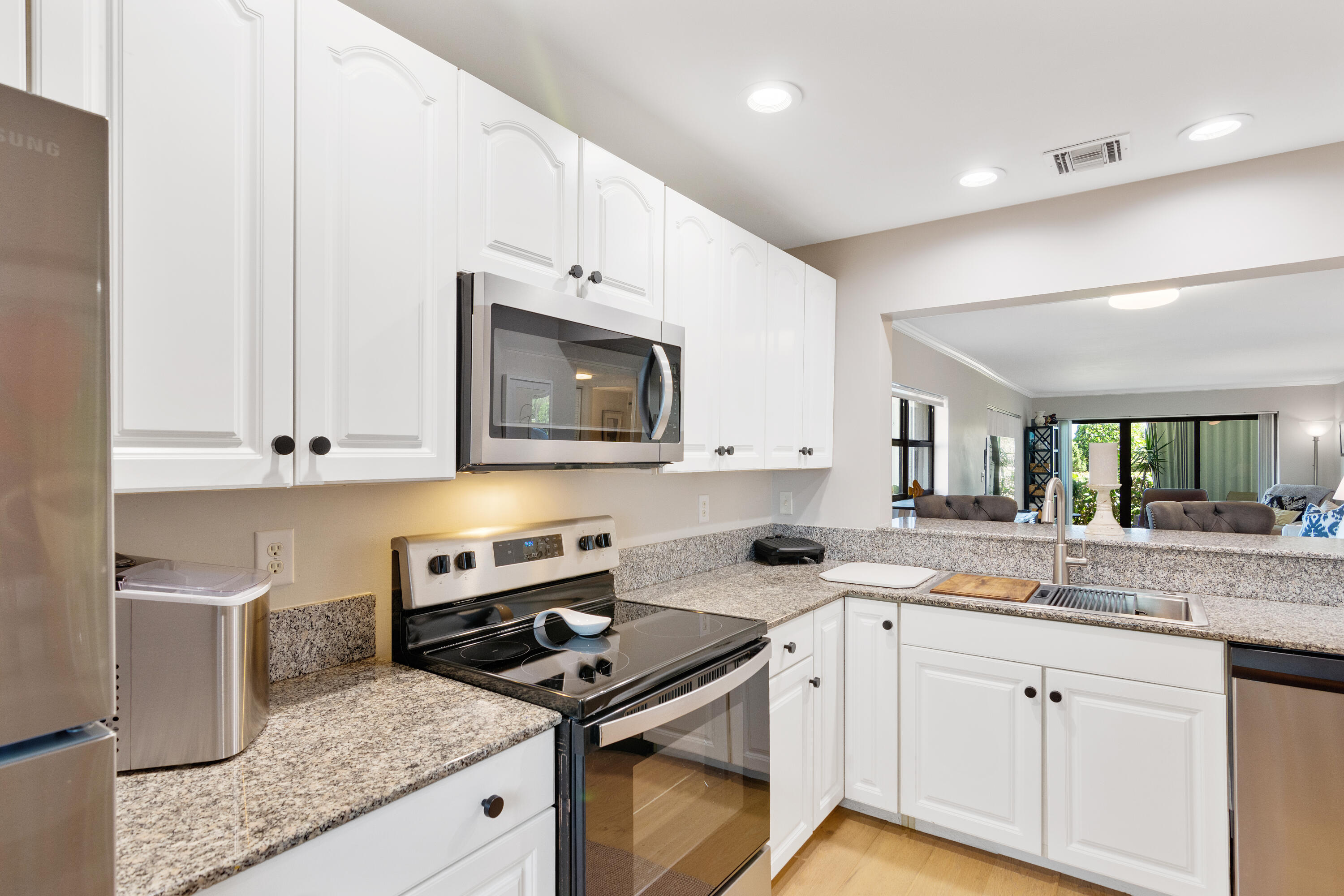 a kitchen with granite countertop a sink stove and microwave