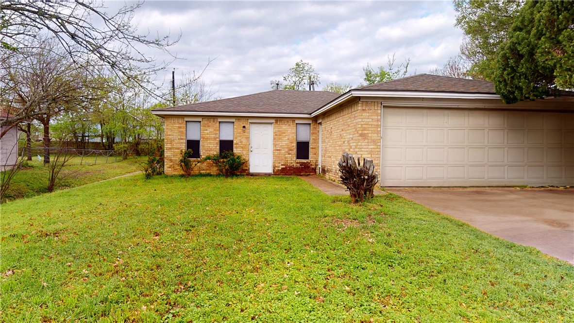 Single story home with a garage and a front yard