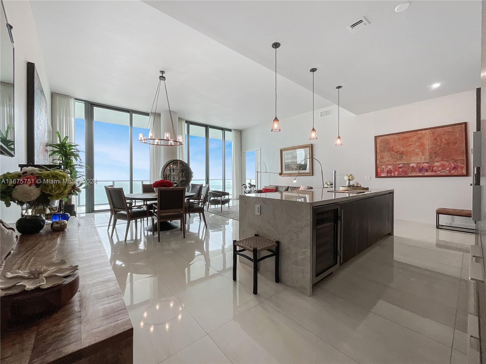 a view of a kitchen with kitchen island stainless steel appliances a stove a sink a counter and chairs