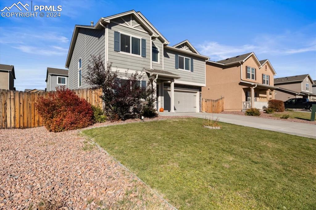 View of front of property featuring a garage and a front lawn