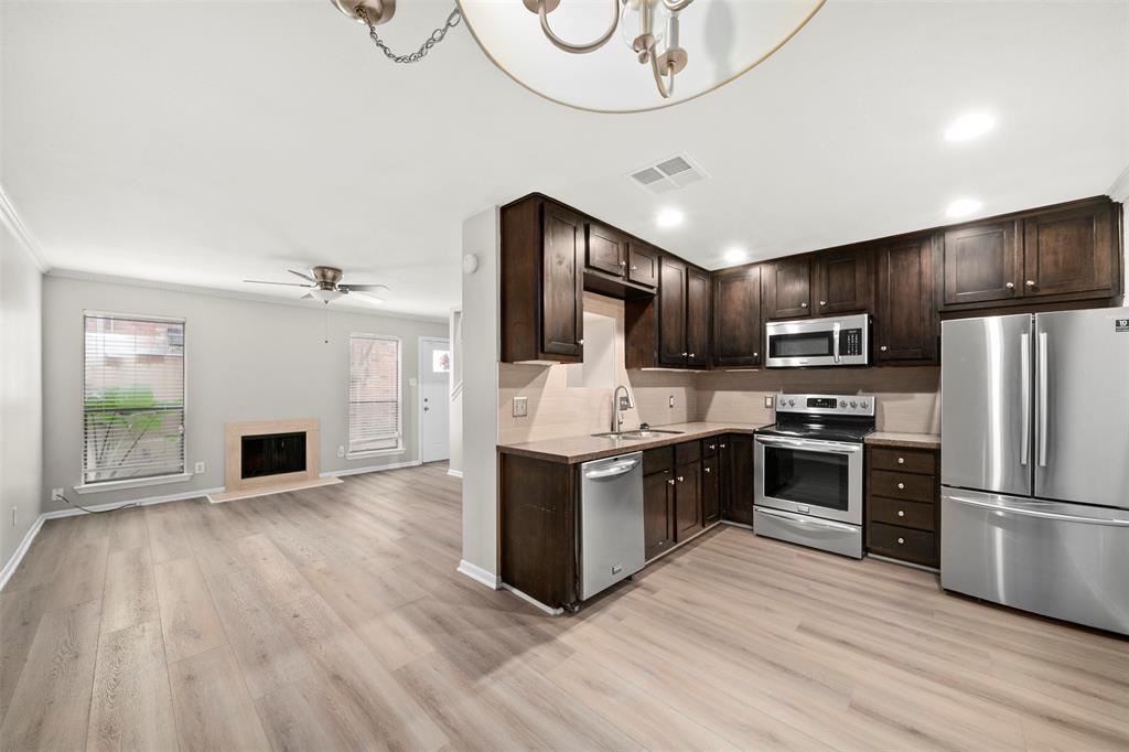 a kitchen with granite countertop a refrigerator oven a kitchen island wooden floors and stainless steel appliances