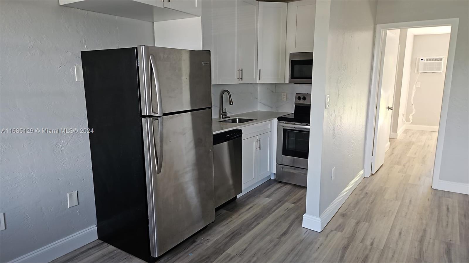 a kitchen with stainless steel appliances a refrigerator and wooden floor