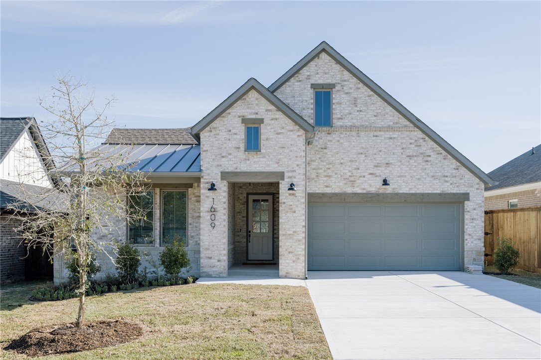 View of front of home with a garage and a front ya