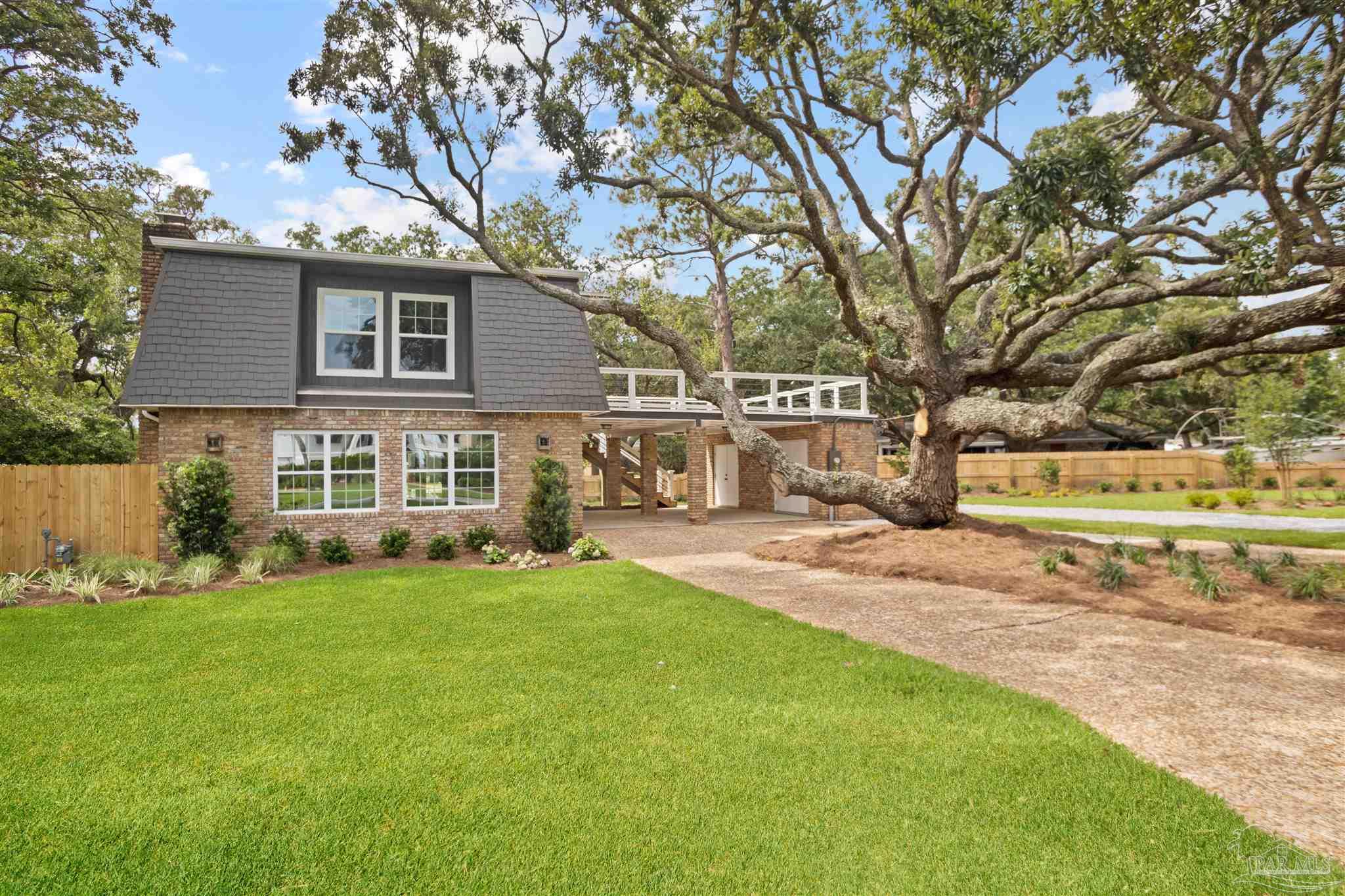 a view of a house with a big yard and large trees