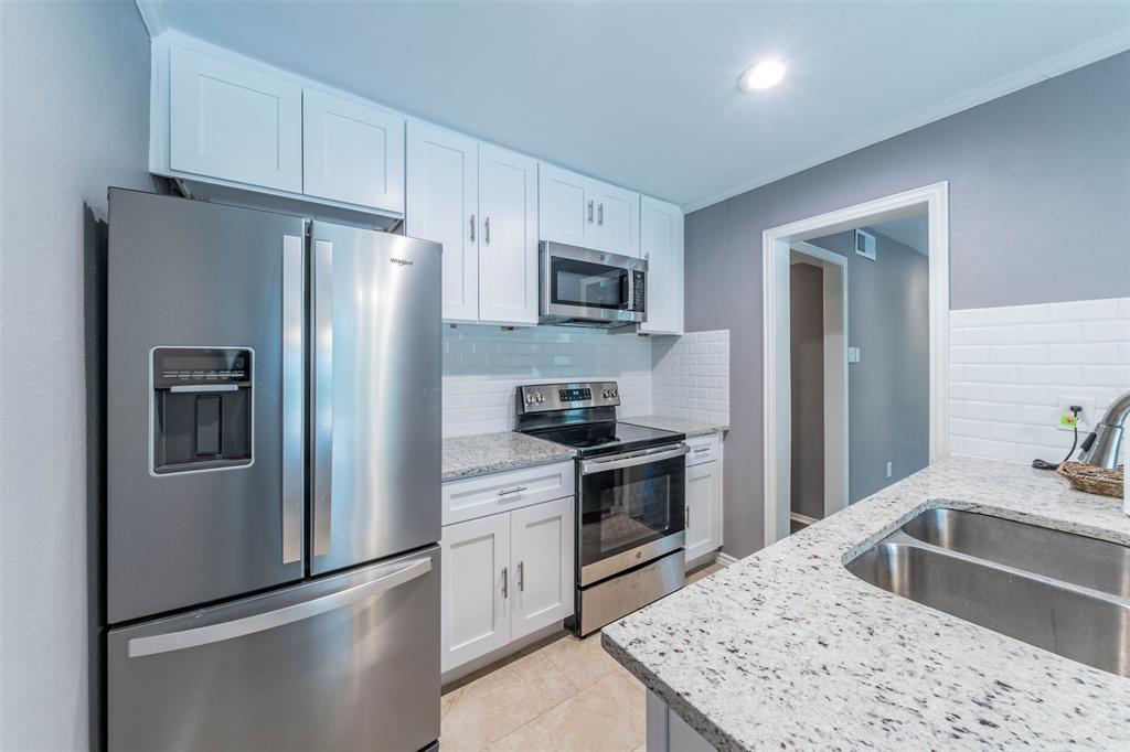 a kitchen with granite countertop a refrigerator stove and sink