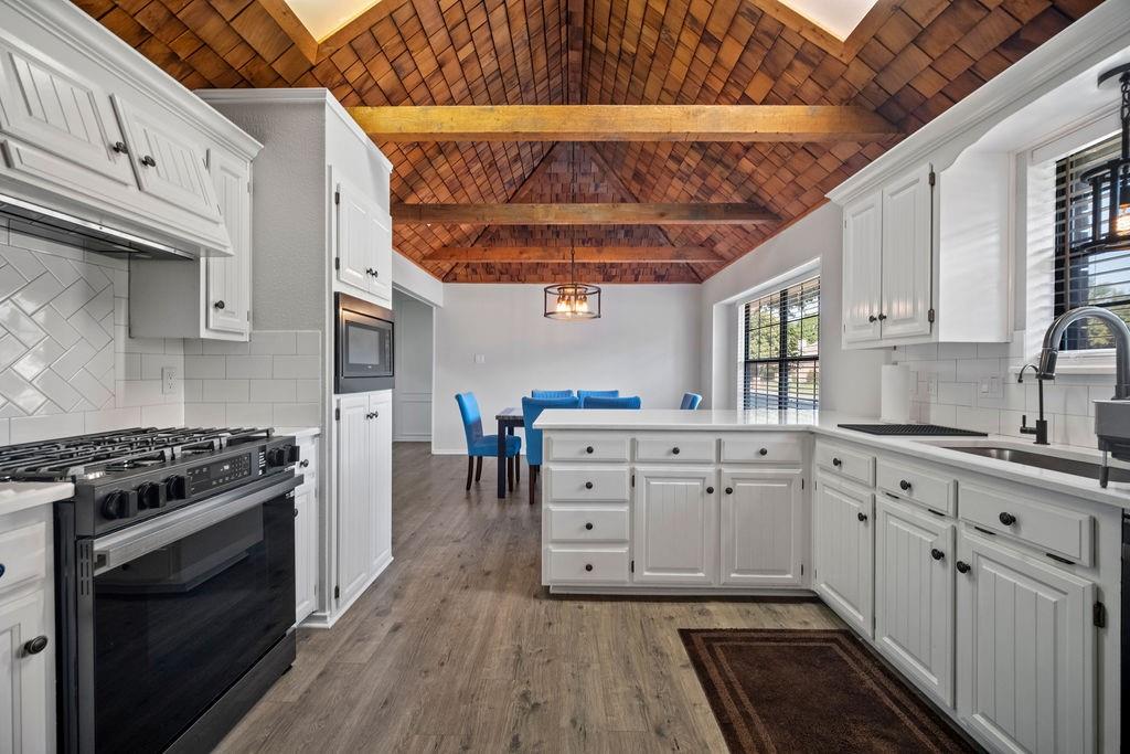 a kitchen with white cabinets stainless steel appliances and wooden floor