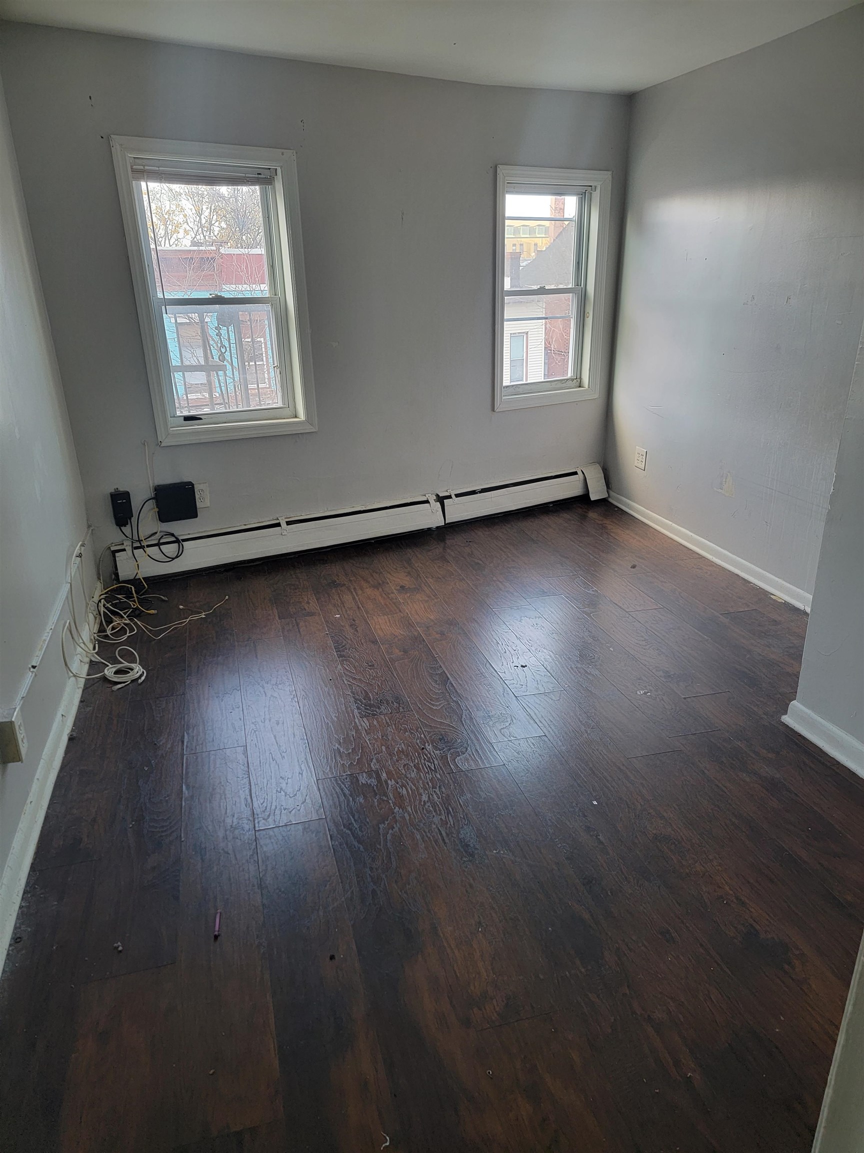 an empty room with wooden floor and windows