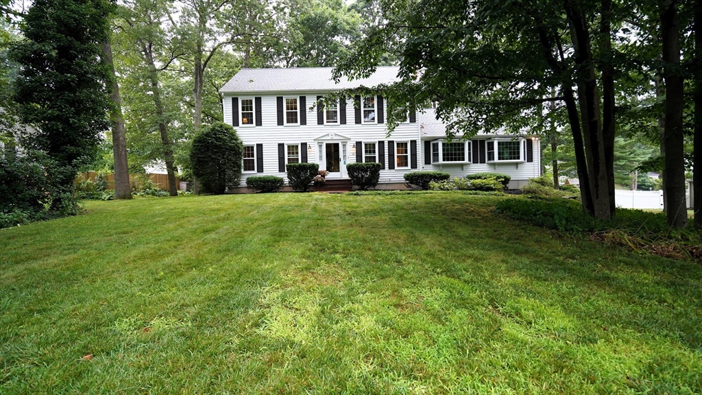 a view of a house with a big yard and large trees