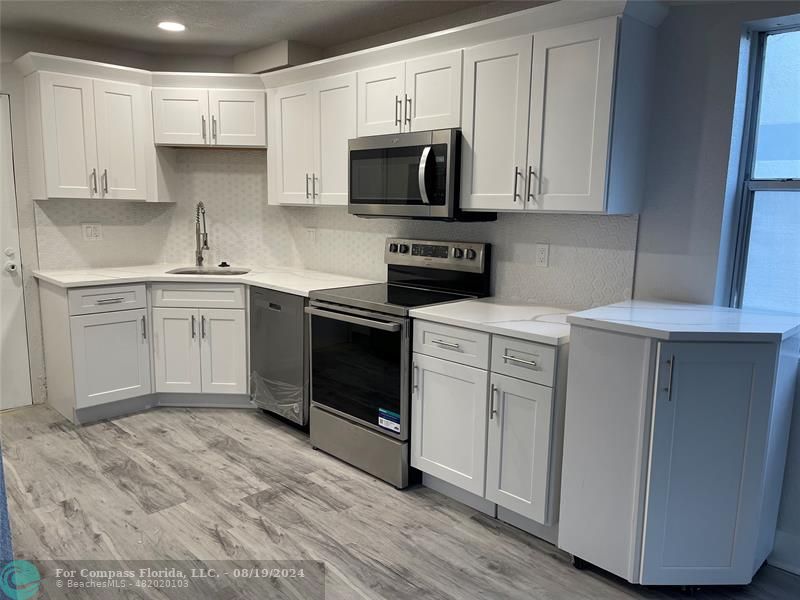 a kitchen with stainless steel appliances granite countertop a stove a sink and a microwave