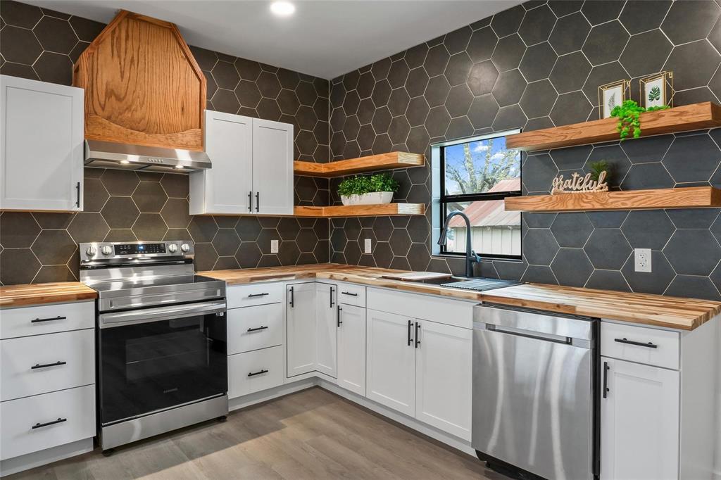 a kitchen with stainless steel appliances a sink a stove and cabinets