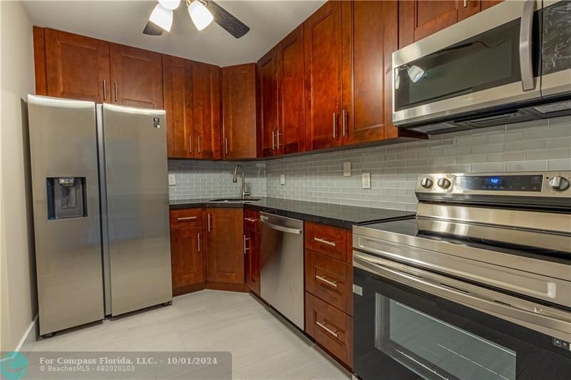 a kitchen with stainless steel appliances granite countertop a refrigerator and a microwave