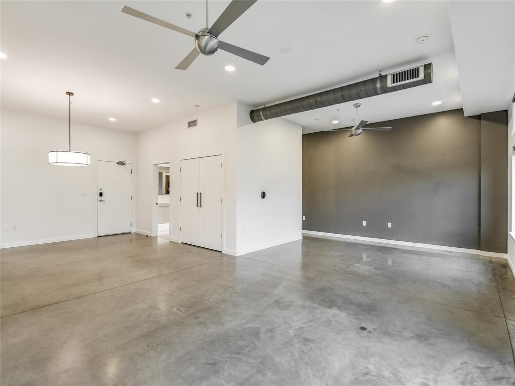 an empty room with an entryway and chandelier fan