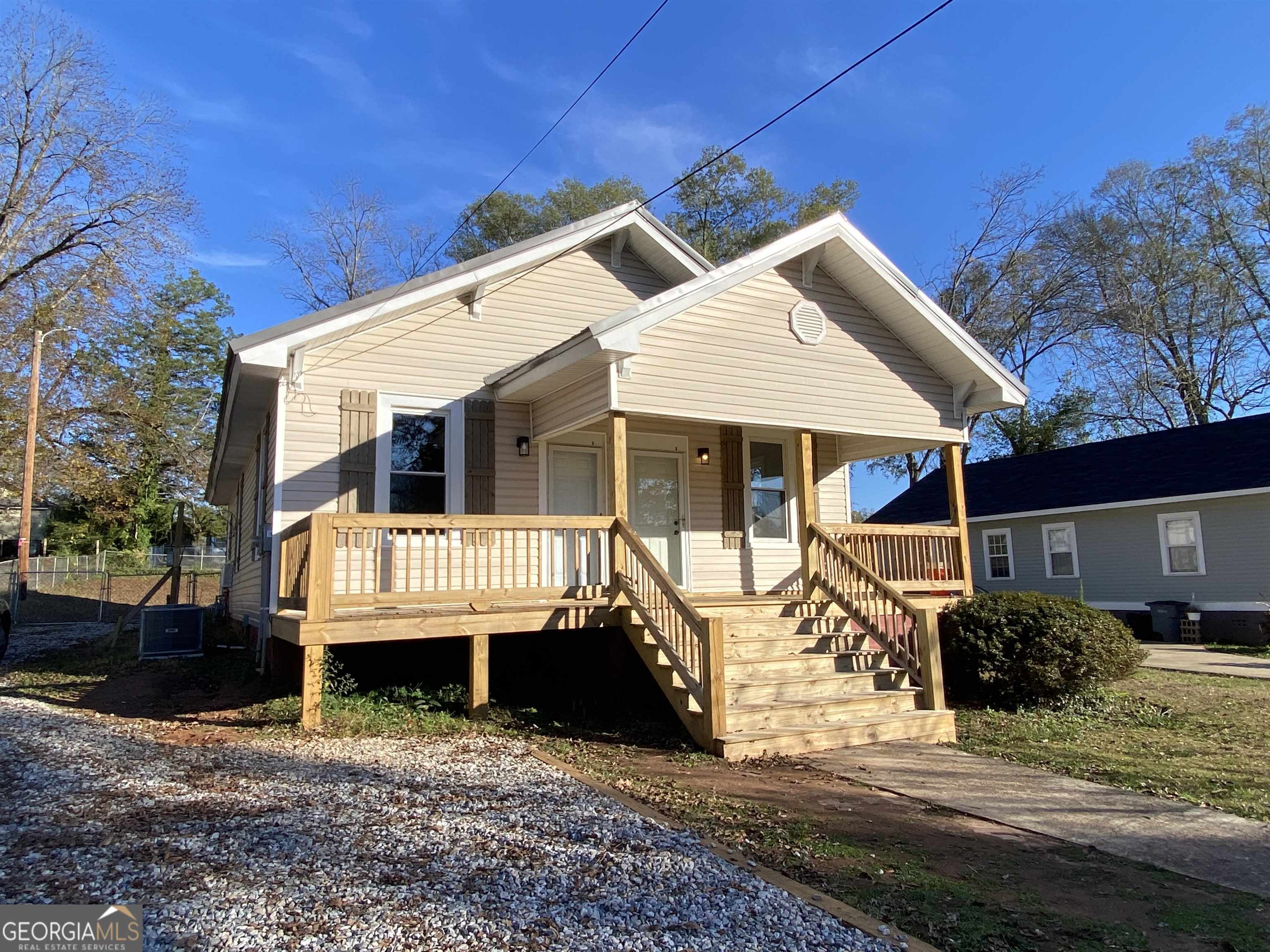 a view of a house with a yard chairs and wooden fence