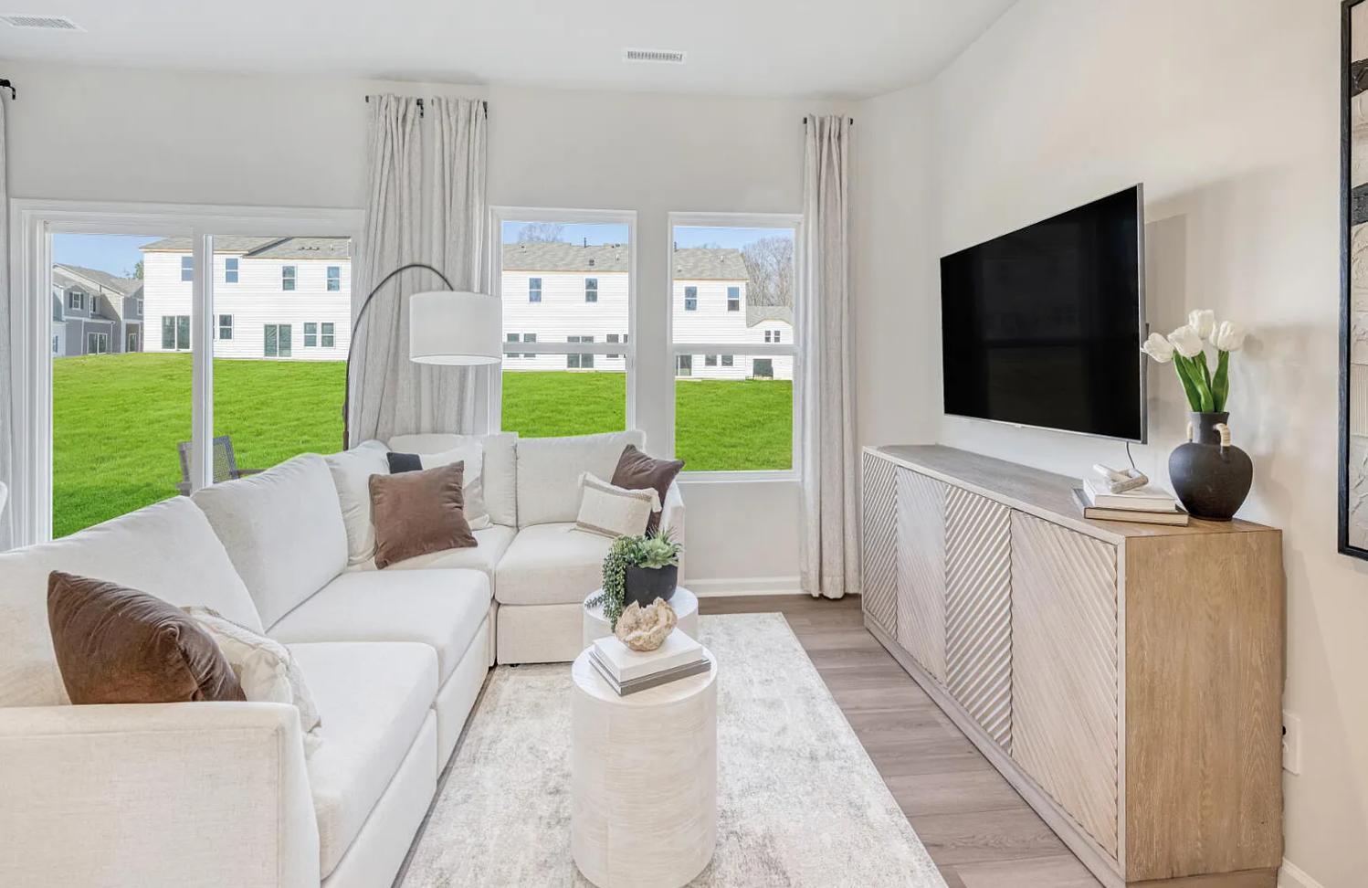 a living room with furniture tv and a floor to ceiling window