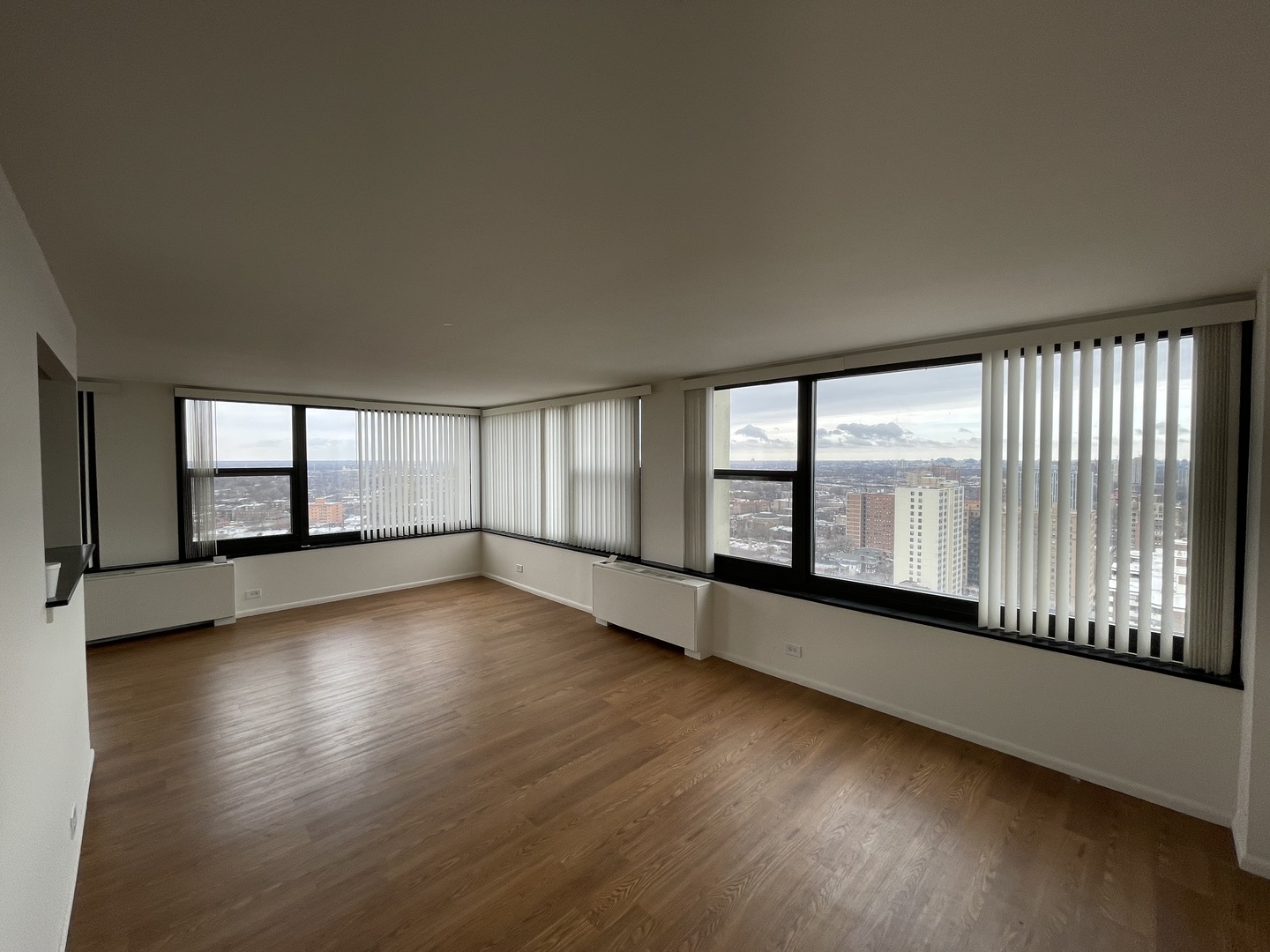 a view of an empty room with wooden floor and a window