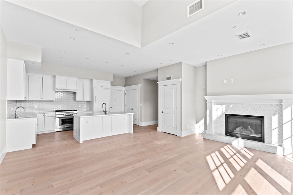 a living room with stainless steel appliances furniture a fireplace and wooden floor