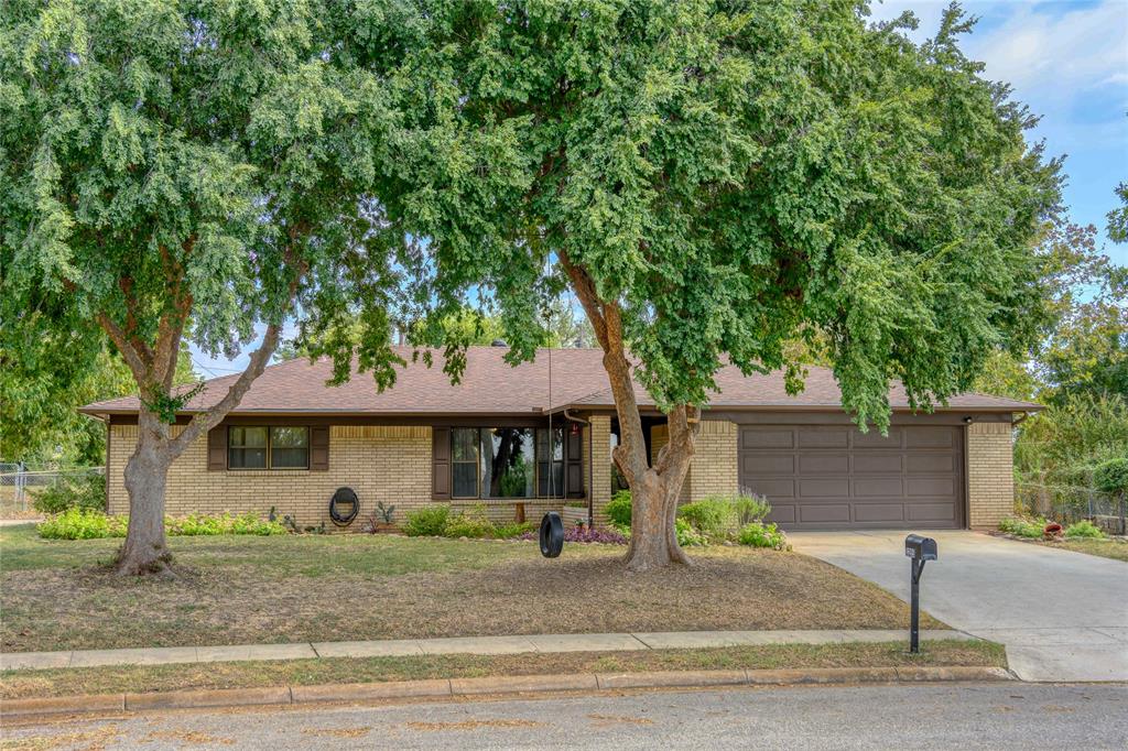 a front view of a house with a garden and tree