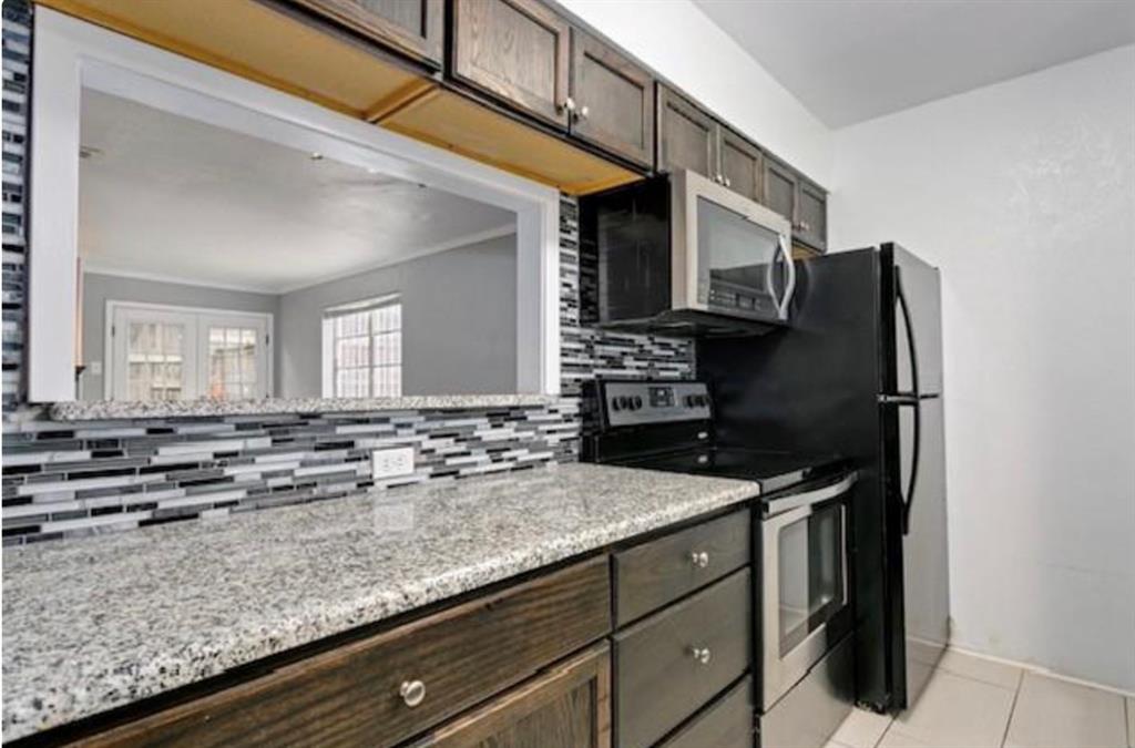 a kitchen with granite countertop a sink and a refrigerator