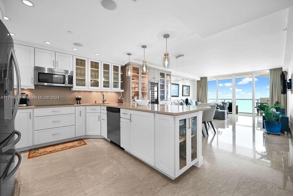 a kitchen with kitchen island granite countertop lots of white stainless steel appliances and white cabinets