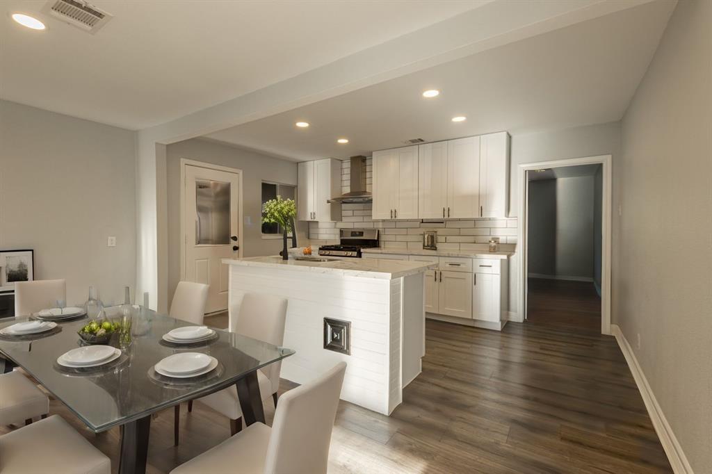 a kitchen with white cabinets stainless steel appliances and dining table