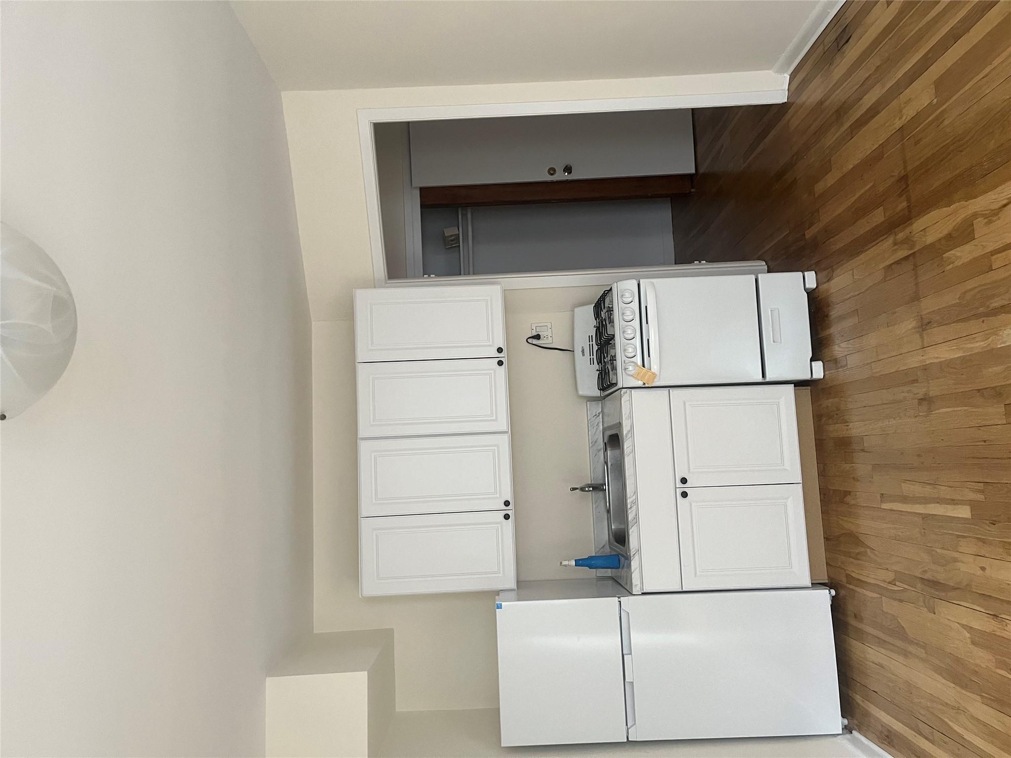 Kitchen with stove, hardwood / wood-style floors, fridge, and sink