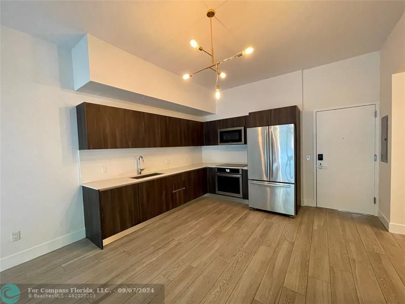 a kitchen with stainless steel appliances a refrigerator and wooden floor