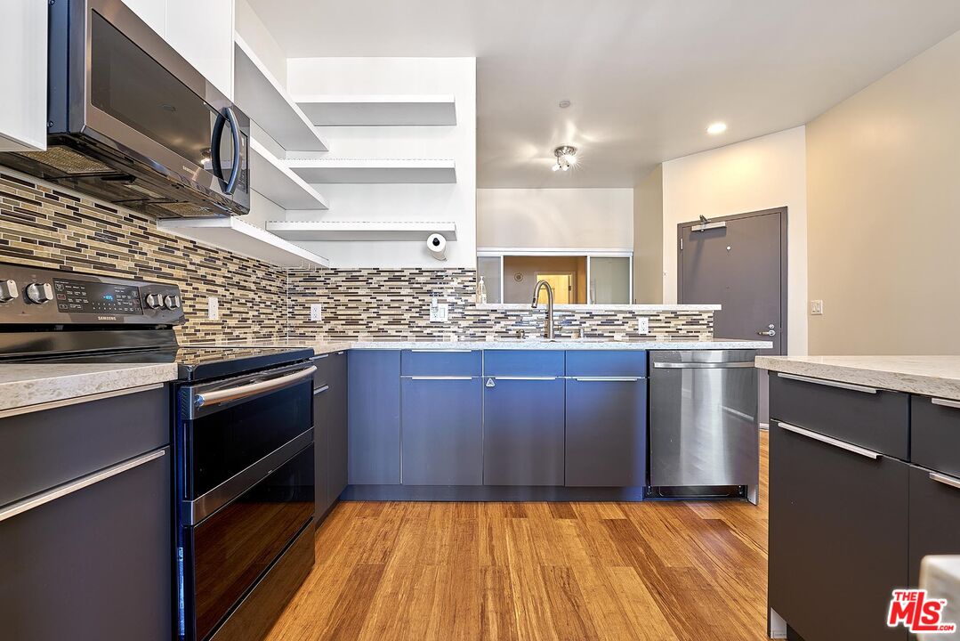 a kitchen with stainless steel appliances granite countertop a stove a sink and a microwave