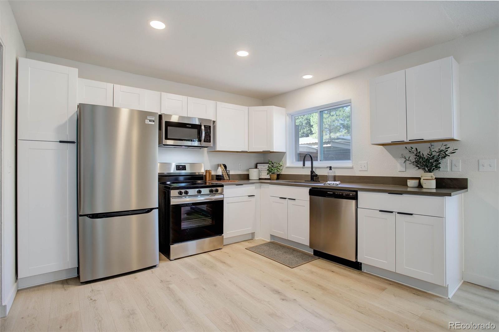 a kitchen with granite countertop a refrigerator stove top oven and sink