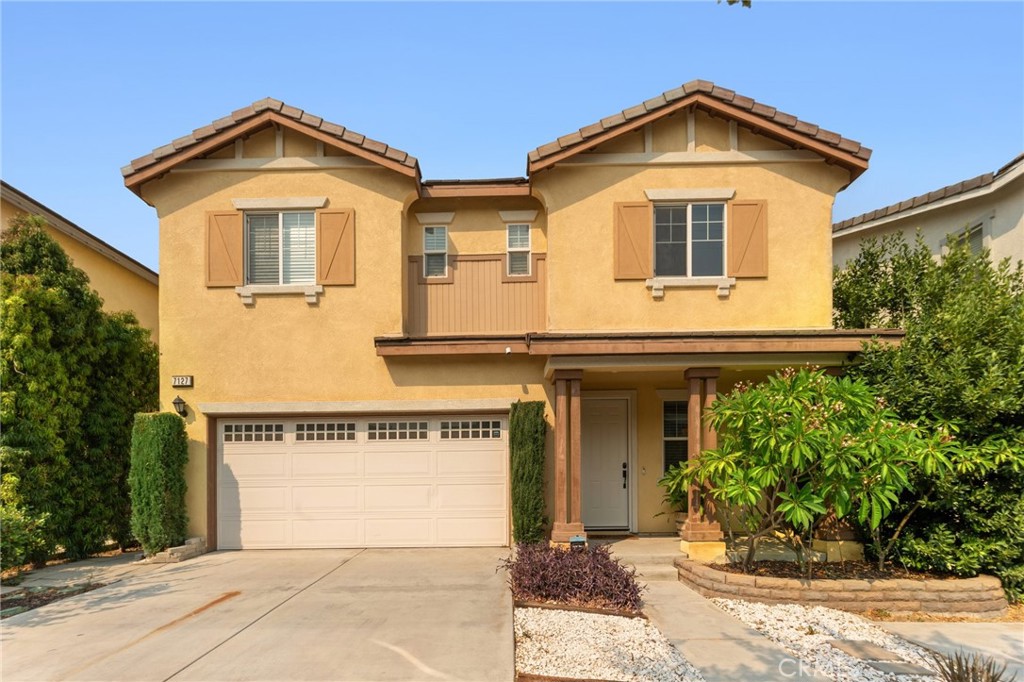 This inviting two-story home features a welcoming front porch, a spacious two-car garage, and attractive landscaping. The exterior is highlighted by classic shutters and a well-maintained façade, making it a perfect choice for comfortable family living.