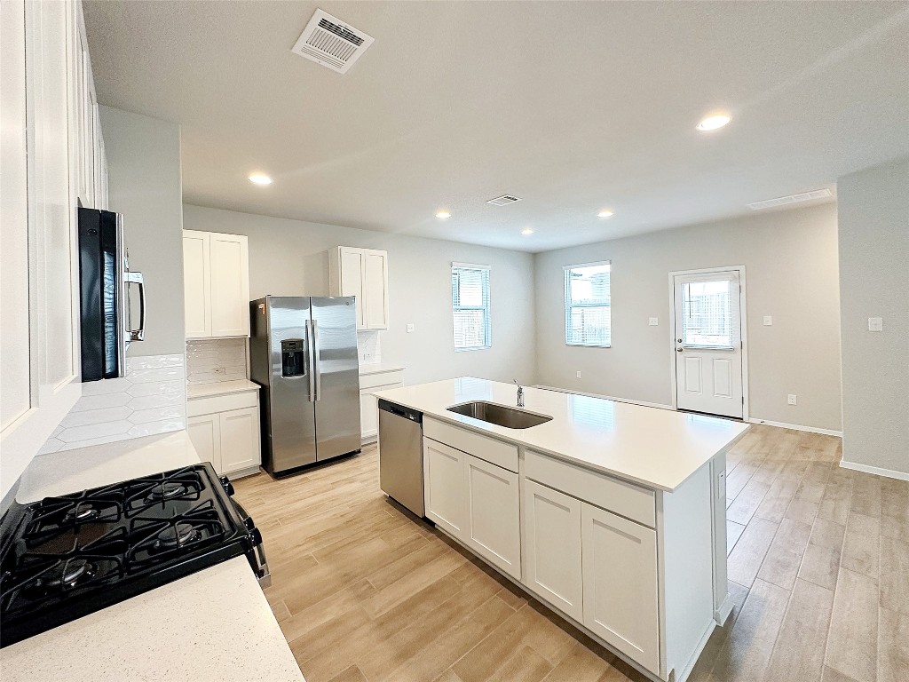 a kitchen with white cabinets and stainless steel appliances