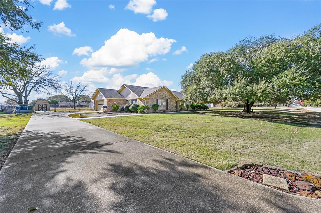 View of front of house featuring the driveway , a shed, a front yard, and a garage