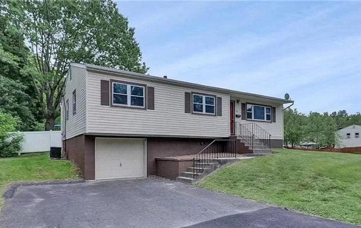 Split foyer home featuring a garage and a front yard