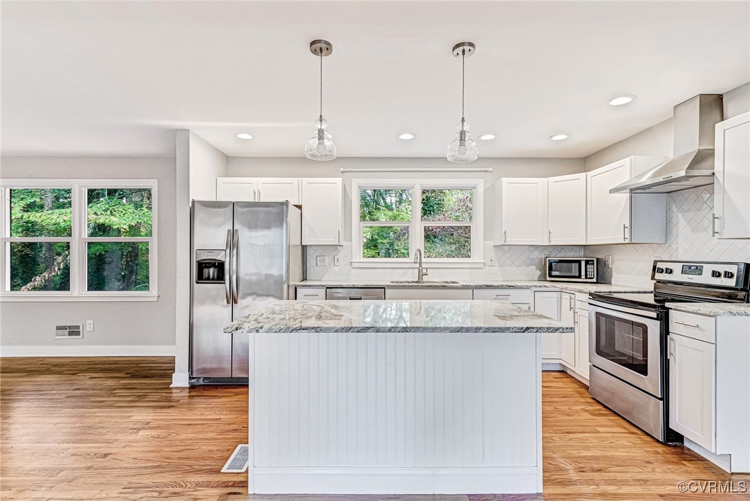 a kitchen with stainless steel appliances granite countertop a stove a sink and a refrigerator