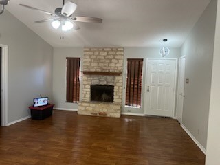 a view of a livingroom with a fireplace a ceiling fan and kitchen view