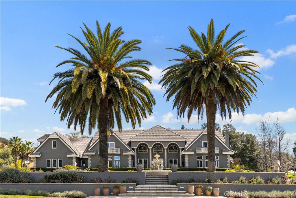 front view of a house with a yard and palm trees