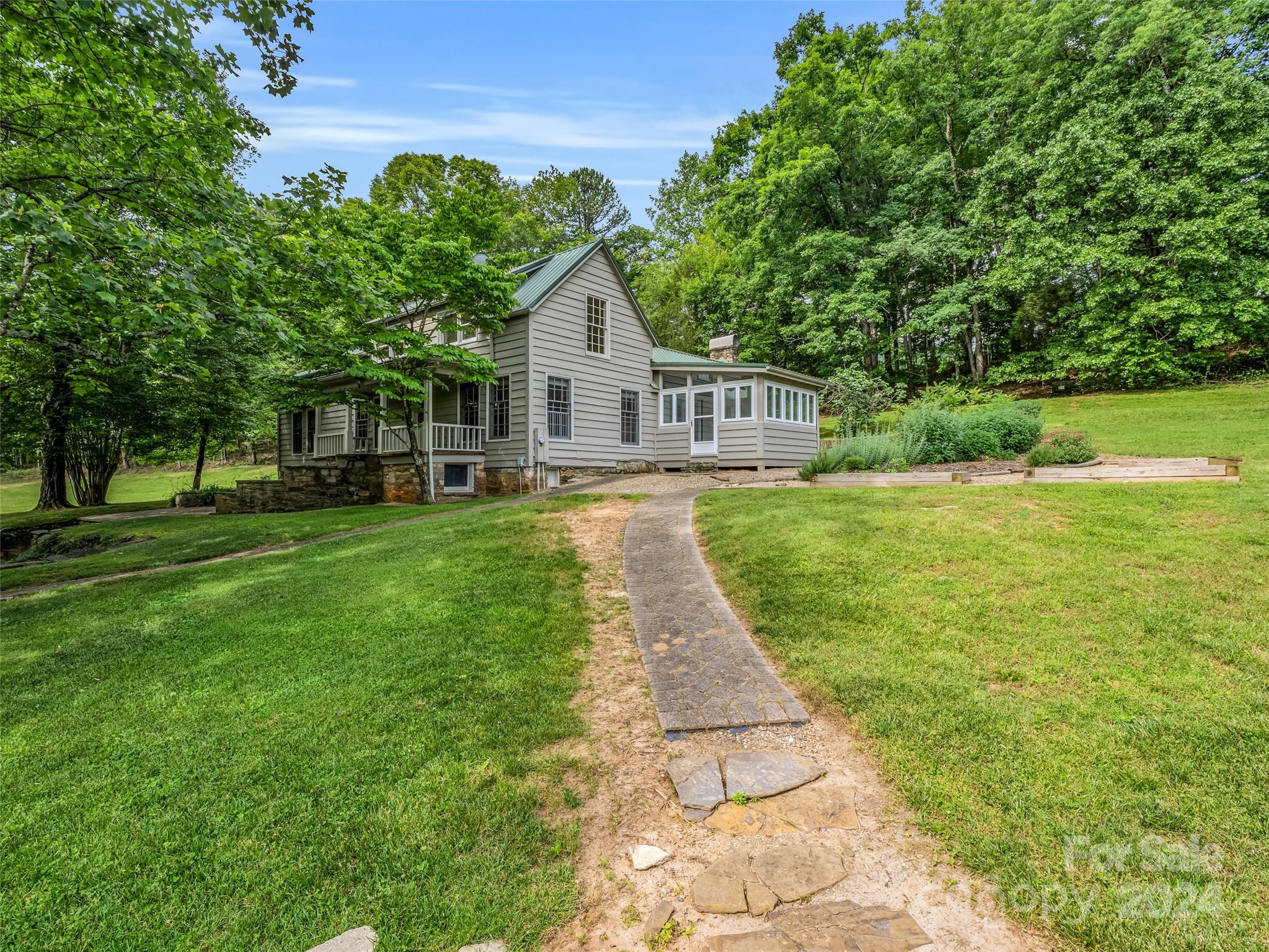 a view of a house next to a big yard with large trees and plants