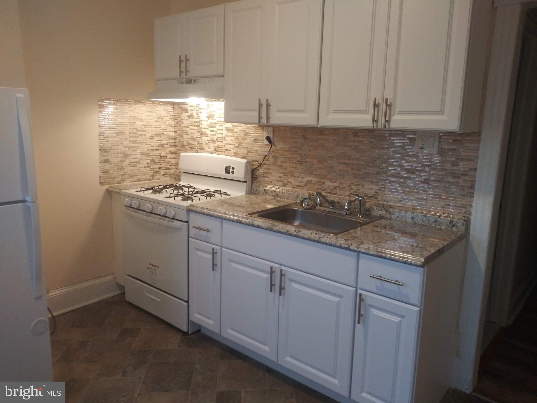 a kitchen with granite countertop white cabinets and white appliances